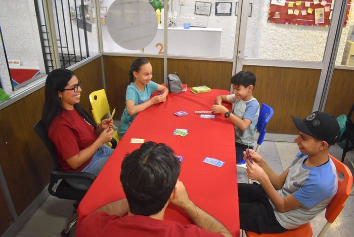 Grupo de alumnos jugando juntos en mesa roja.