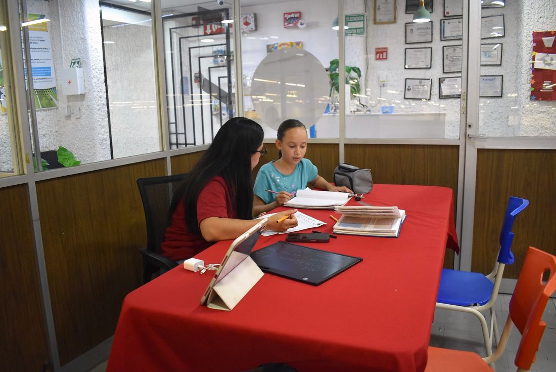 Tutora de MatheComics acompañando de forma individual a una alumna con tablet y cuadernos.